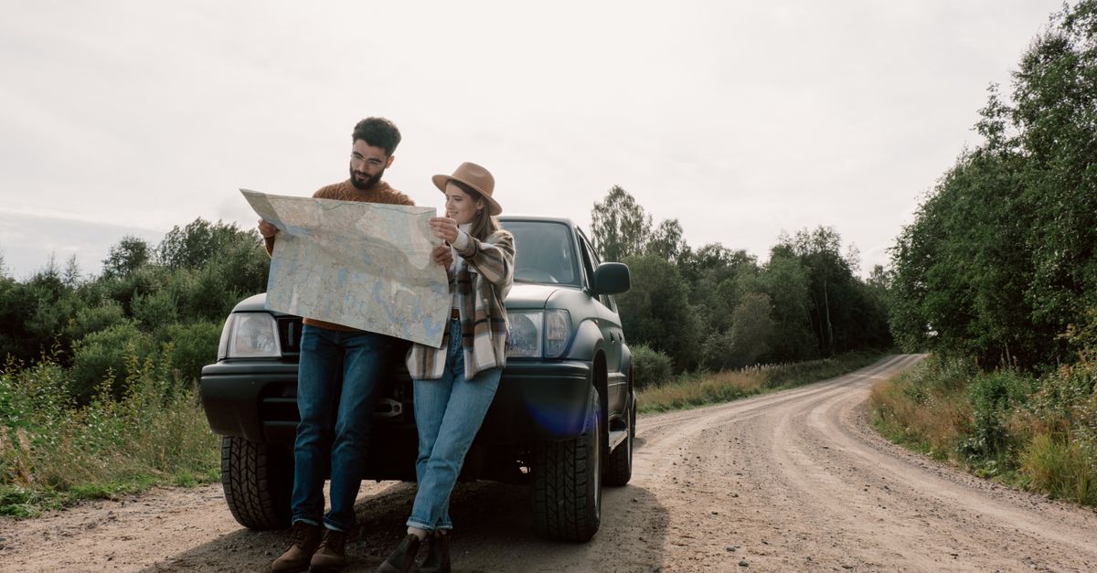 Técnico rural observando un mapa de paisaje junto a un camino de tierra
